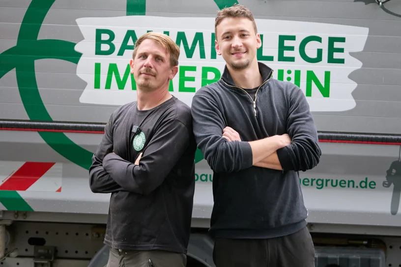 Luka Möller neben dem Inhaber von Baumpflege Immergrün vor einem Lkw mit der Firmenaufschrift